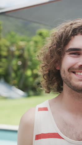 Vertical-video:-Caucasian-male-with-curly-hair-smiling,-green-background,-at-home