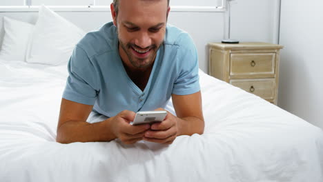 Hombre-Feliz-Acostado-En-La-Cama-Usando-Su-Teléfono-Inteligente-