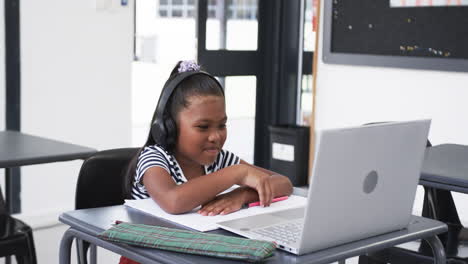 In-a-school-classroom,-a-young-African-American-girl-is-engaged-with-a-laptop