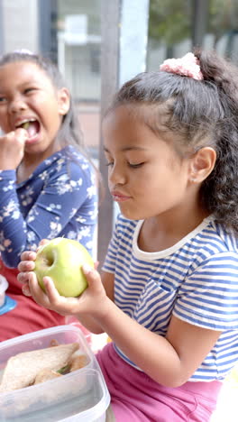 Vertical-video:-In-school,-two-biracial-young-girls-are-enjoying-lunch