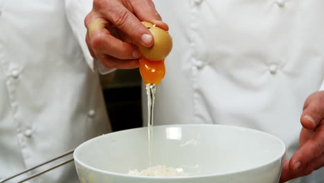 Baker-putting-an-egg-in-a-mixing-bowl