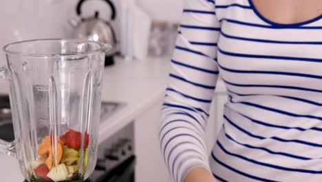Woman-putting-fruits-in-her-blender