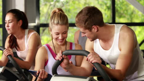 Female-trainer-talking-to-a-man-doing-exercise-bike