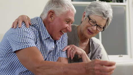 Senior-couple-putting-money-in-piggy-bank