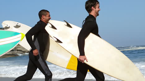 Friends-in-wet-suits-running-into-water