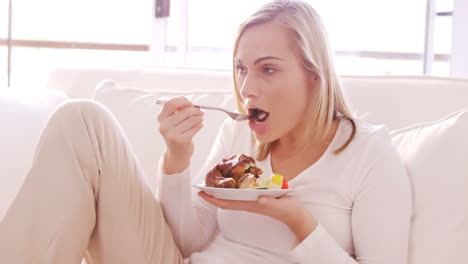 Blonde-woman-eating-chicken-on-a-sofa