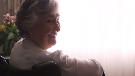 Smiling-senior-woman-sitting-on-wheel-chair