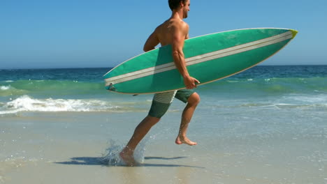 Man-running-into-water-with-surfboard