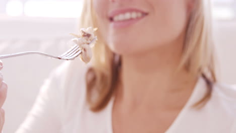 Blonde-woman-eating-chicken-on-a-sofa