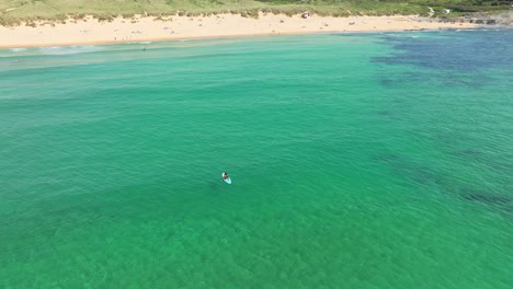 Remos-Aislados-De-Paddle-Boarder-De-Regreso-A-La-Bahía-De-Constantino-En-Cornualles-Con-Un-Drone-Aéreo-Orbitando-Al-Individuo,-Reino-Unido