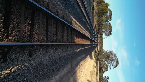 Drones-Volando-A-Baja-Altitud-Sobre-Rieles-De-Tren-En-Un-Paisaje-Rural