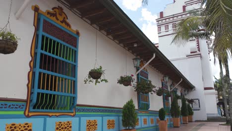 Colorful-house-facade-with-vibrant-window-frames-and-hanging-plants-in-Guatapé,-Colombia