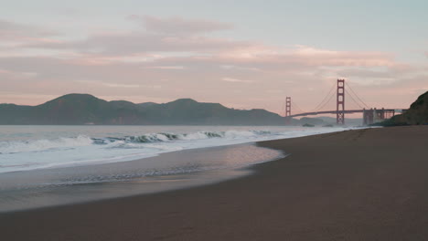 Impresionante-Amanecer-Sobre-El-Puente-Golden-Gate-Con-Olas-Del-Océano-Y-Nubes-Desde-Baker-Beach,-San-Francisco