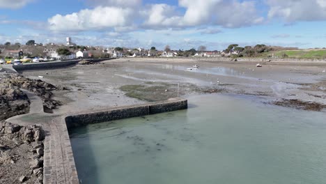 Schnelle-Enthüllung-Des-Hafens-Von-Bordeaux-Guernsey-Bei-Ebbe-Mit-Hafenmauer,-Anlegestelle,-Booten,-Die-Auf-Sand-Trocknen,-Strand-Und-Hütten-Im-Hintergrund-An-Einem-Hellen-Tag