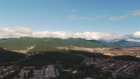 Panning-drone-view,-sunlit-mountains-and-city-near-Salta,-Argentina