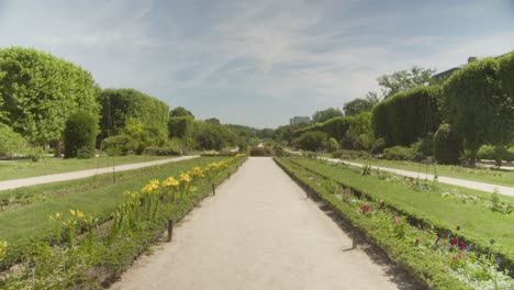 A-serene-path-lined-with-flowers-in-the-Jardin-des-Plantes,-Paris-on-a-sunny-day