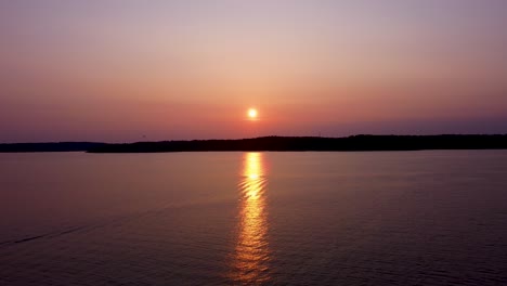 Yellow-sunset-reflects-on-calm-sea-water-in-Stockholm-Archipelago,-aerial-view