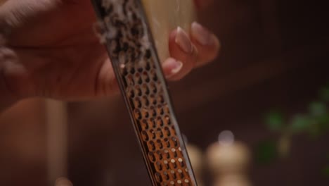 Hands-Shredding-Cheese-with-a-Cheese-Grater---Close-Up