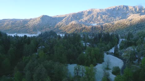 Eine-Atemberaubende-Aussicht-Auf-Den-Schneebedeckten-Berg,-Der-über-Dem-Nebelverhangenen-Wald-Im-Tal-Thront,-Und-Die-Kurvenreiche-Straße