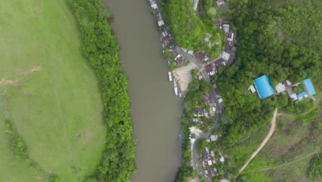 Una-Exuberante-Orilla-Del-Río-Con-Edificios-Y-Vegetación-En-Florencia,-Colombia,-Vista-Aérea