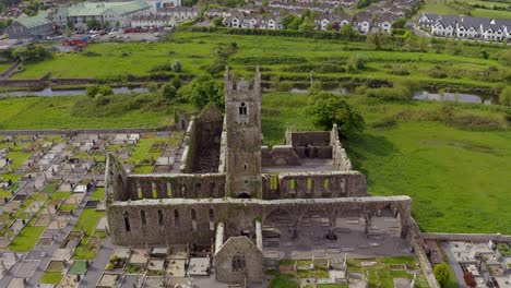 Kloster-Von-Claregalway-In-Der-Mitte,-Während-Eine-Drohne-über-Einem-Friedhof-In-Der-Nähe-Des-Flusses-Clare-Herabsteigt