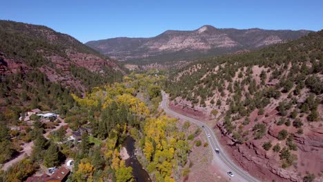 Highway-running-through-red-sandstone-mountains-and-next-to-a-river-in-Colorado-during-the-fall-on-a-cloudless-day