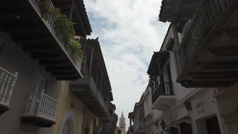 Historische-Straße-Von-Cartagena-Mit-Gebäuden-Aus-Der-Kolonialzeit-Und-Balkonen-Unter-Einem-Teilweise-Bewölkten-Himmel