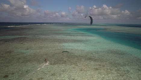 Kiteboarder-Se-Desliza-Sobre-Las-Aguas-Turquesas-De-Un-Arrecife-De-Coral-Bajo-Un-Cielo-Parcialmente-Nublado