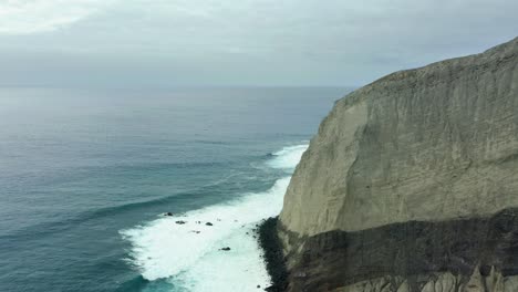 Steep-rocky-cliffs-drop-off-into-coastal-waters-on-overcast-day,-San-Benedicto-Revillagigedo-Islands-Mexico