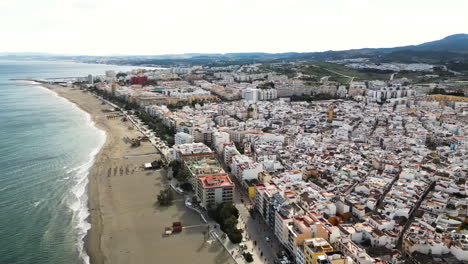 Beautiful-cityscape-of-Estepona-between-sea-and-mountains,-aerial-panoramic-view