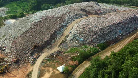 Drone-flyover-capturing-abandoned-sanitary-landfill-with-large-piles-of-unsorted-solid-wastes-in-the-illegal-dump-site,-concept-of-environmental-sustainability,-global-warming,-climate-change