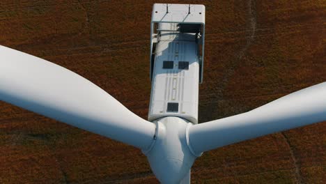 Wind-Turbine-Aerial-Tilt-Down-Ascending-Drone-and-Farmland-in-the-Background