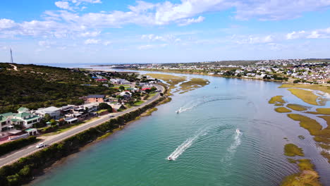 Motorized-watercraft-cruising-on-Goukou-estuarine-river-in-Still-Bay,-aerial