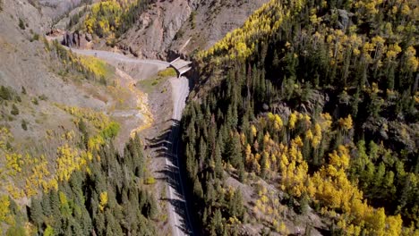 Tilt-up-of-the-Million-Dollar-Highway-carving-through-the-Rocky-Mountains-in-Colorado-lined-by-golden-aspens-during-the-fall