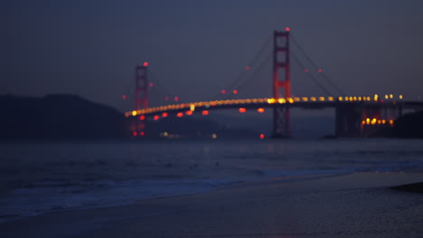 Stunning-sunrise-over-Golden-Gate-Bridge-with-ocean-waves-and-clouds-from-Baker-Beach,-San-Francisco