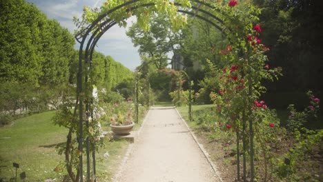 Malerischer-Gartenweg-Mit-Blühenden-Rosen-Und-Grünem-Torbogen-Im-Naturmuseum-Von-Paris