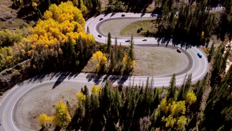 Cars-driving-the-S-curve-of-the-Million-Dollar-Highway-in-Colorado-lined-with-golden-aspens-during-the-fall,-aerial