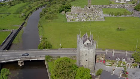 Claregalway-catle-tilting-up-to-Friary-and-cemetery-by-river-clare,-aerial-pullback