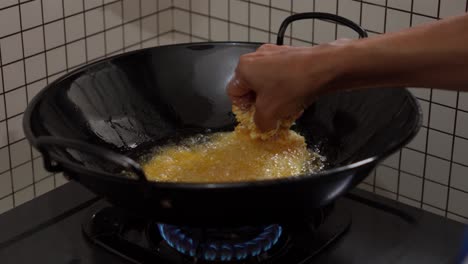 A-hand-holds-a-panko-breaded-chicken-tender,-ready-to-be-fried