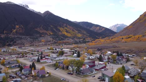 Drone-flying-over-Silverton-Colorado,-former-mining-town,-with-the-Rocky-Mountains-on-either-side-during-the-fall-in-the-late-afternoon
