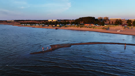 Aerial-view-of-father-and-kids,-playing-in-water-on-the-coast-of-Kalajoki,-sunset-in-Finland