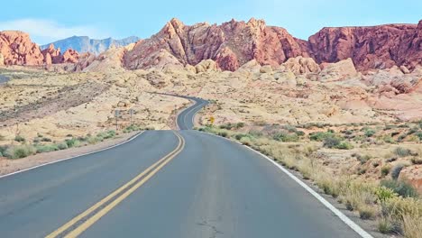 El-Valle-Del-Fuego-Conduce-En-Primera-Persona-Con-Un-Pintoresco-Paisaje-Circundante-De-Rocas-Y-Montañas-Rojas,-Nevada,-EE.UU.