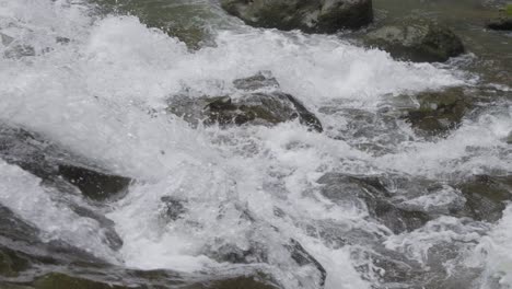 Primer-Plano-De-Agua-Burbujeante-Cayendo-Sobre-Las-Rocas-De-La-Cascada-Goa-Rang-Reng-En-Bali,-Indonesia,-Capturada-En-Cámara-Lenta