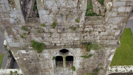 Torre-Del-Convento-De-Claregalway-En-El-Centro-De-Un-Dron-Aéreo-Que-Retrocede-Sobre-Restos-De-Piedra