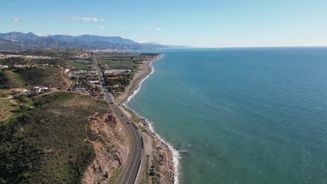 Vuelo-De-Drones-Sobre-La-Carretera-De-La-Costa-Oeste-De-Guernsey-En-Un-Día-Tranquilo-Y-Soleado-Que-Muestra-El-Mar,-Las-Playas,-Las-Rocas-Y-Los-Promontorios-Distantes