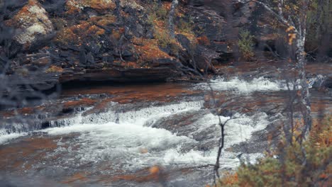 Rapids-on-the-shallow-mountain-river-surrounded-by-the-autumn-forest