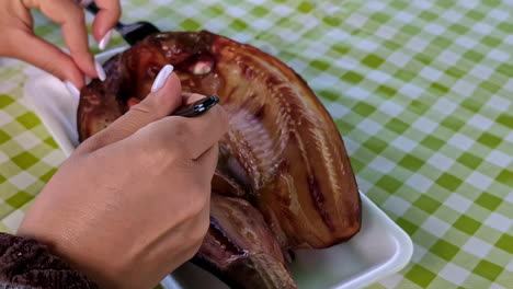 Close-up-shot-of-female-hands-cutting-through-grilled-fresh-cooked-seafood-dish-served-on-a-restaurant-table