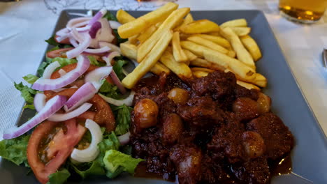 Ein-Eintopfgericht-Mit-Zwiebeln,-Tomaten,-Salat-Und-Pommes