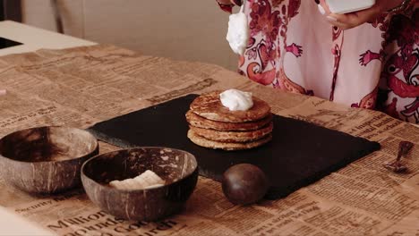 Frau-Verteilt-Sahne-Auf-Pfannkuchen-Und-Bereitet-Ein-Köstliches-Frühstück-Vor