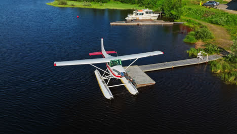AERIAL:-Seaplane-docked-at-a-pier-on-lake-Inari,-sunny,-summer-day-in-Finland